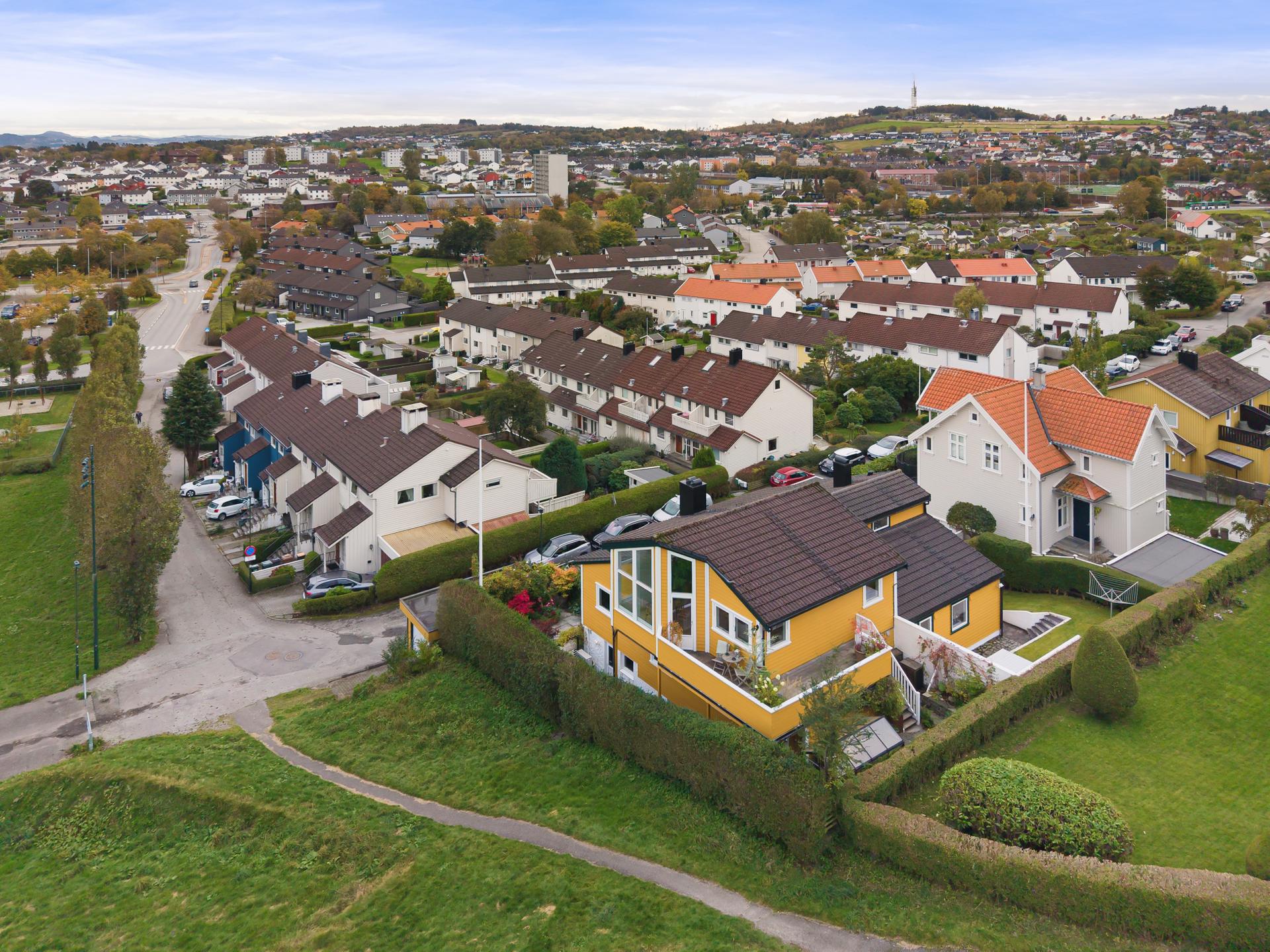 Boligen ligger fint plassert i det skrånende terrenget og grenser direkte til et åpent, grønt friområde. Bilde nummer 3 av 3