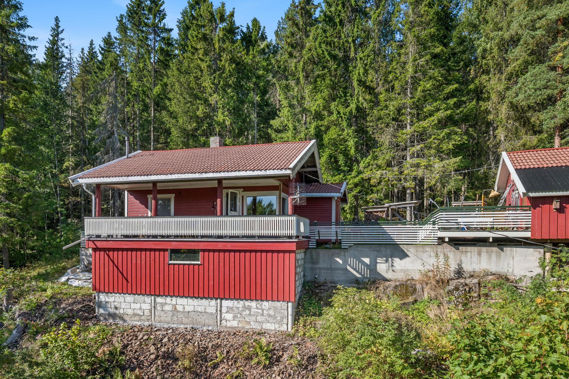 Hytta ligger usjenert til i et skrånet terreng, omkranset av skog.. Bilde nummer 2 av 3