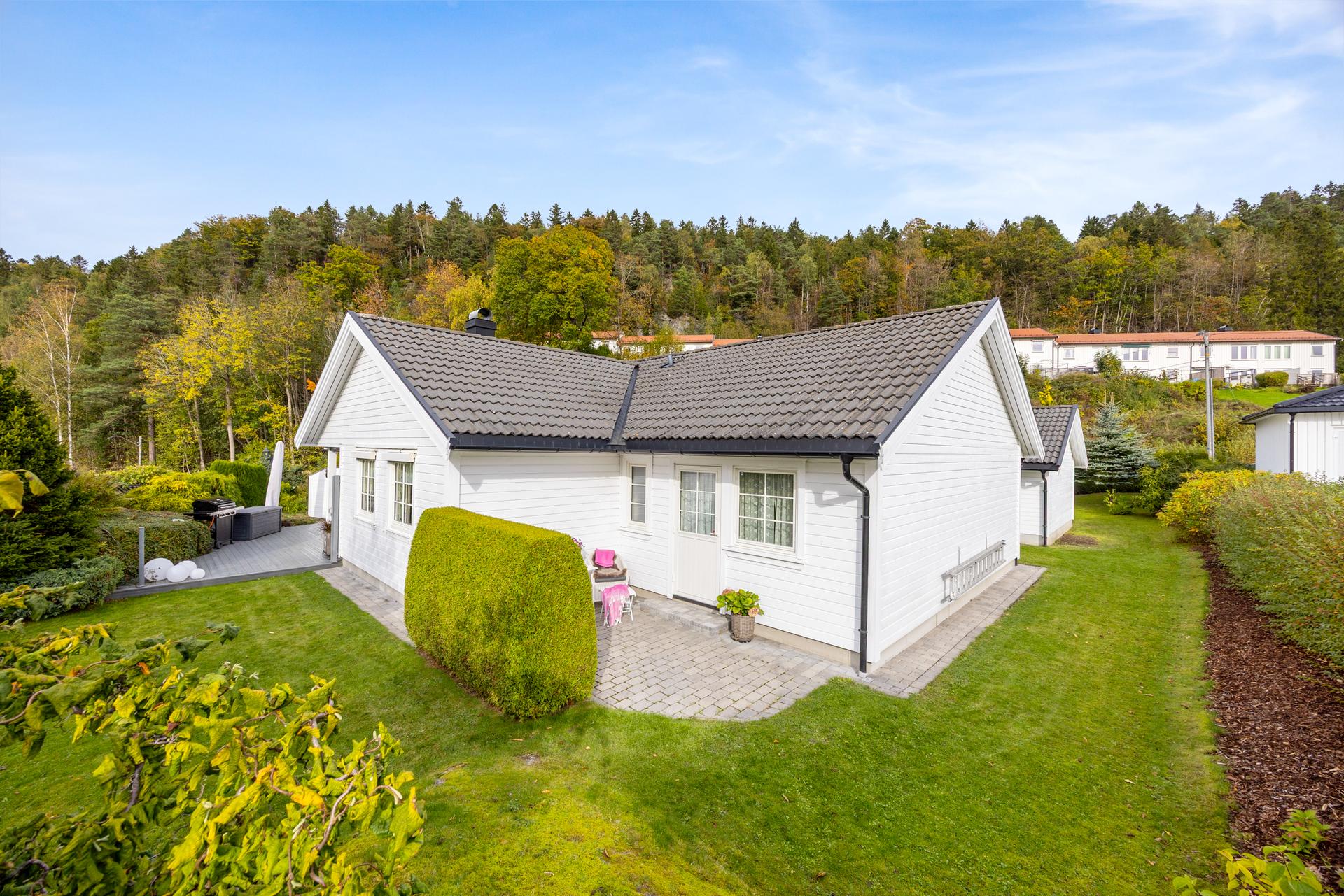 Tomten er pent anlagt med plen, hekk, variert beplantning og belegningsstein, og fremstår svært velholdt. Boligen har adkomst til hage og terrasser ut fra stue og hovedsoverom. . Bilde nummer 3 av 3