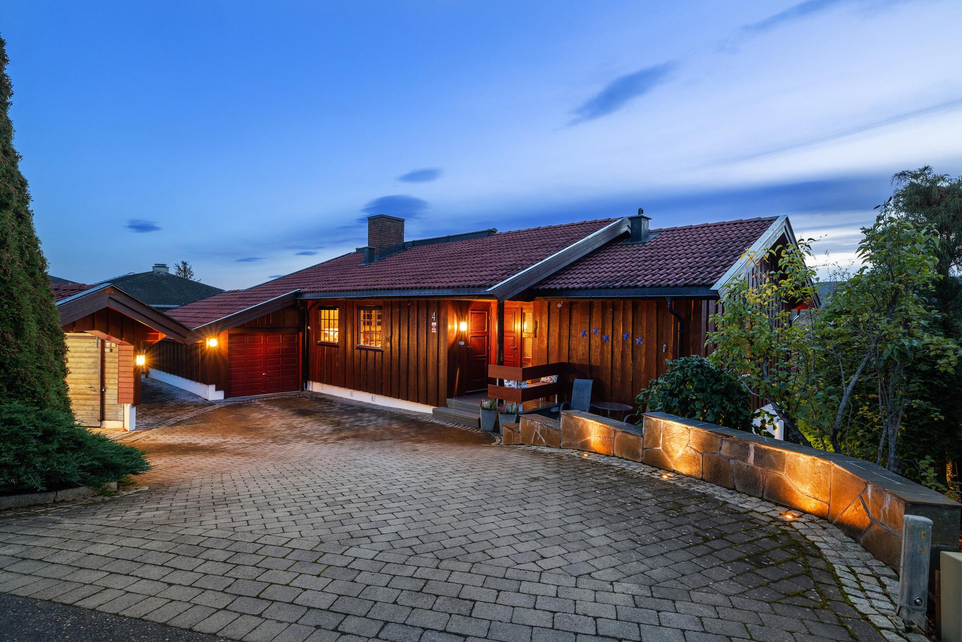 Innkjøringen er rammet inn av forstøtningsmur med integrert belysning og brostein i randsonene. En nydelig plass å komme hjem til.. Bilde nummer 2 av 3