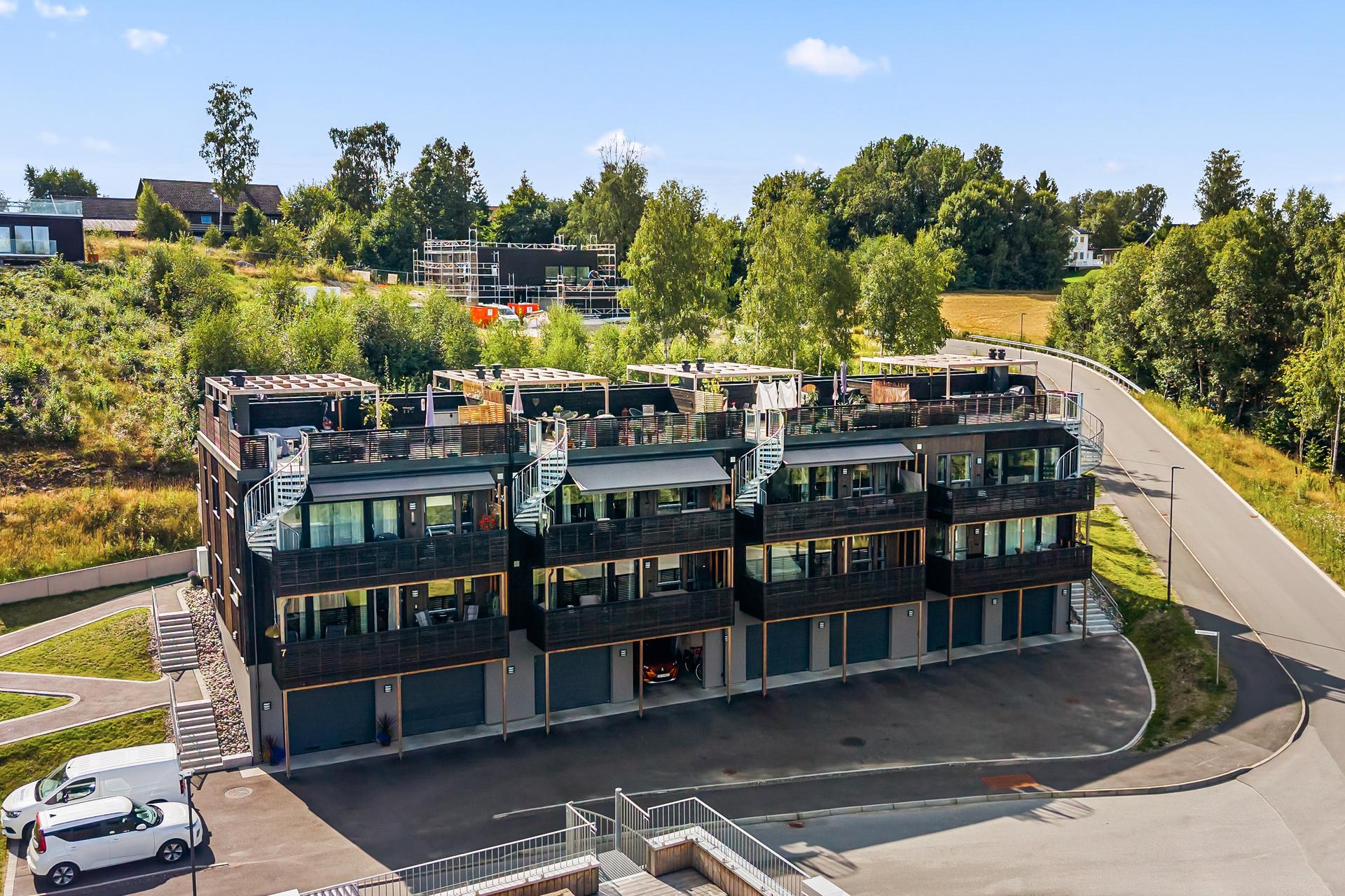 Bygget fra 2025 har en moderne arkitektur med fasader i behandlet trepanel. Leiligheten ligger i 1. etasje og har atkomst til takterrassen, via ut. Bilde nummer 2 av 3
