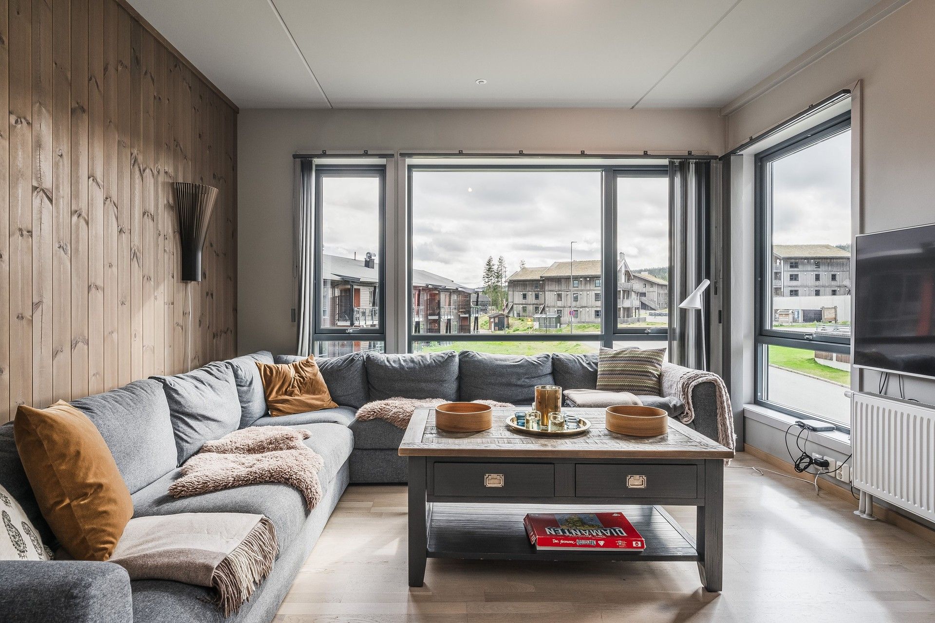 En kombinasjon av eikeparkett og panelvegger gir en lun og moderne atmosfære i oppholdsrommet.. Bilde nummer 2 av 3