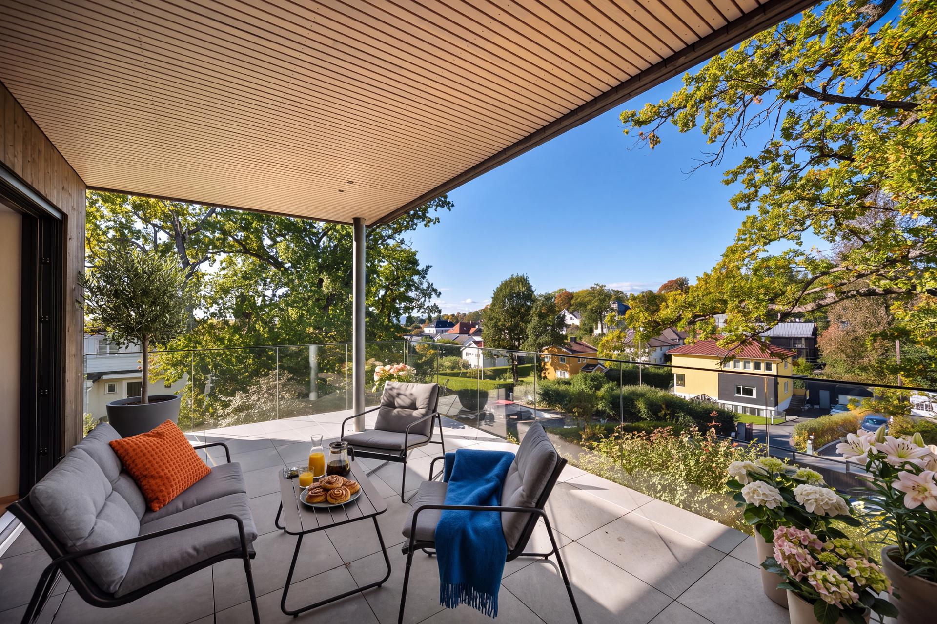 Overbygget terrasse med utsyn mot grønne omgivelser. AI-møblert for å illustrere innredningsmuligheter.. Bilde nummer 1 av 3