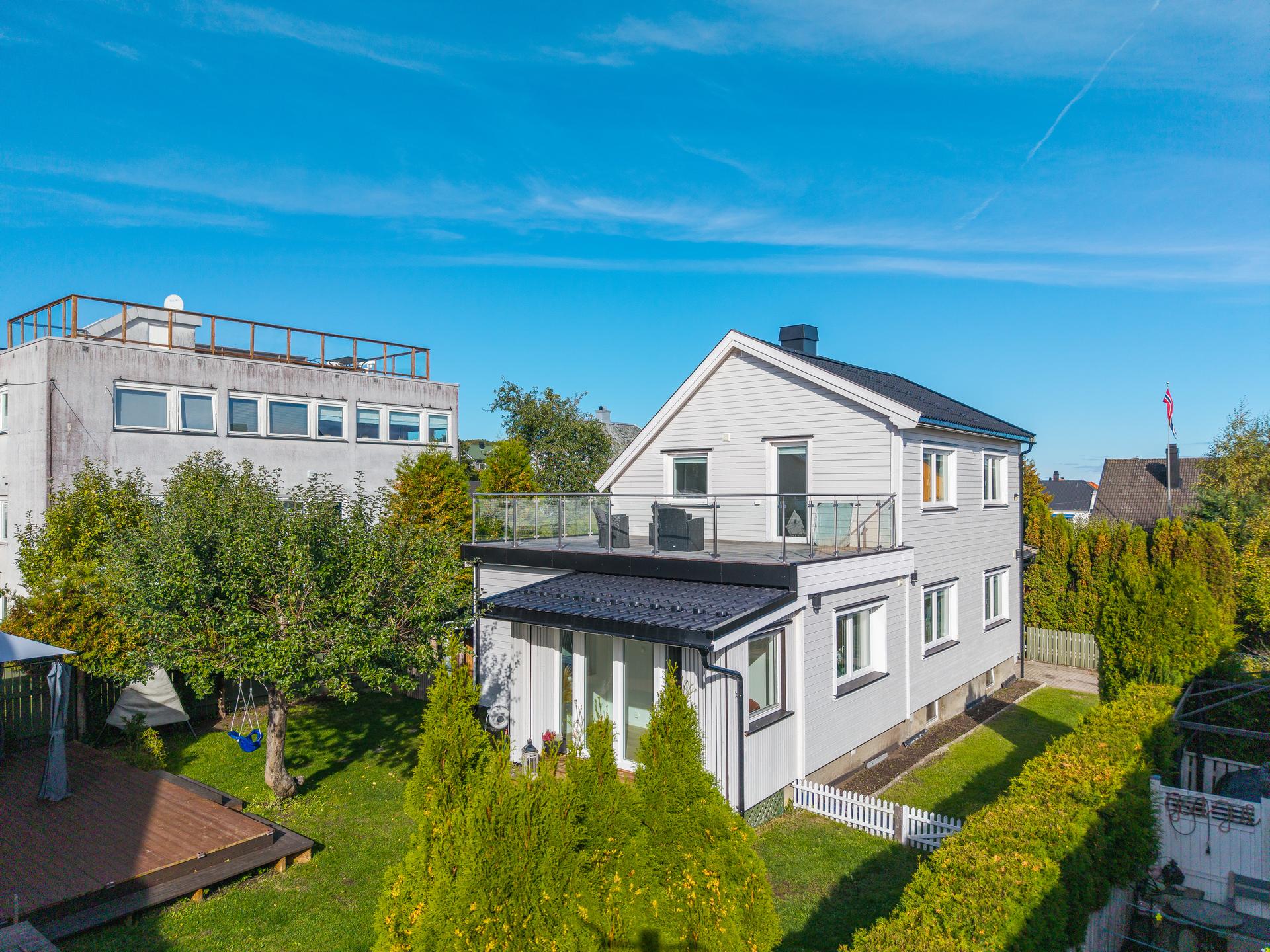 Enebolig over tre plan med opparbeidet hage, tilhørende garasje og stor takterrasse.. Bilde nummer 2 av 3