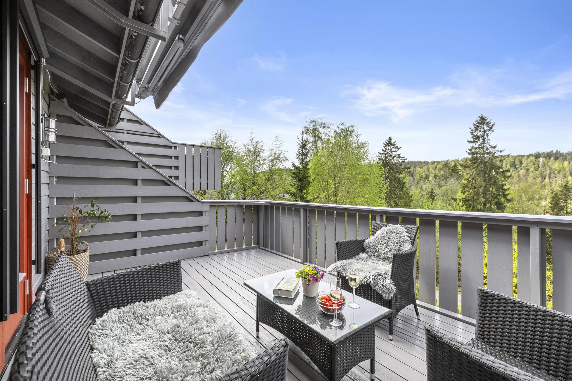 Romslig veranda med god plass til sittegruppe og utsikt mot grønne omgivelser.. Bilde nummer 2 av 3