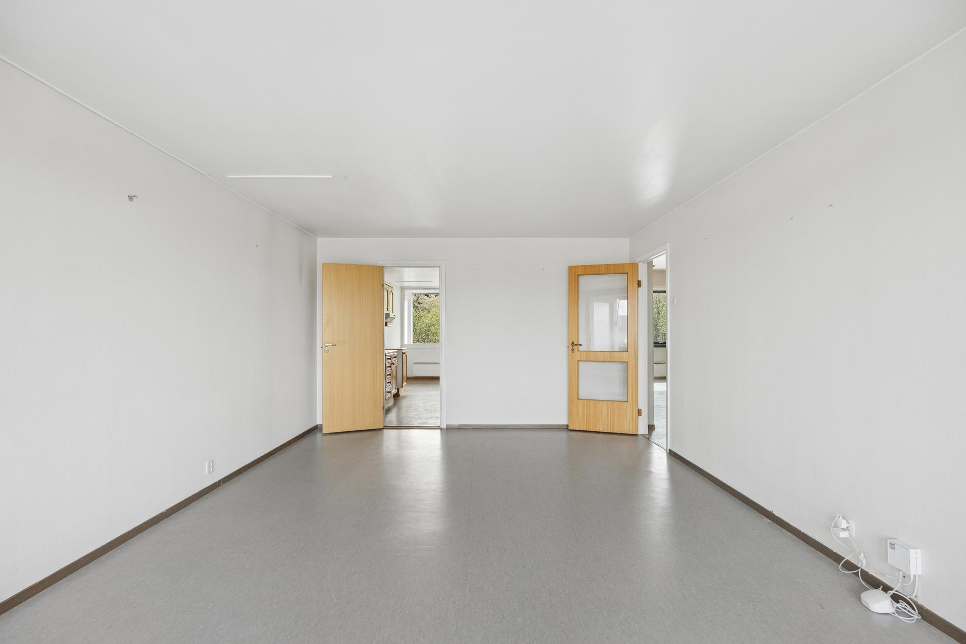 Stuen har god plass til både sofagruppe og spisebord, med dør med glassfelt mot entréen.. Bilde nummer 3 av 3
