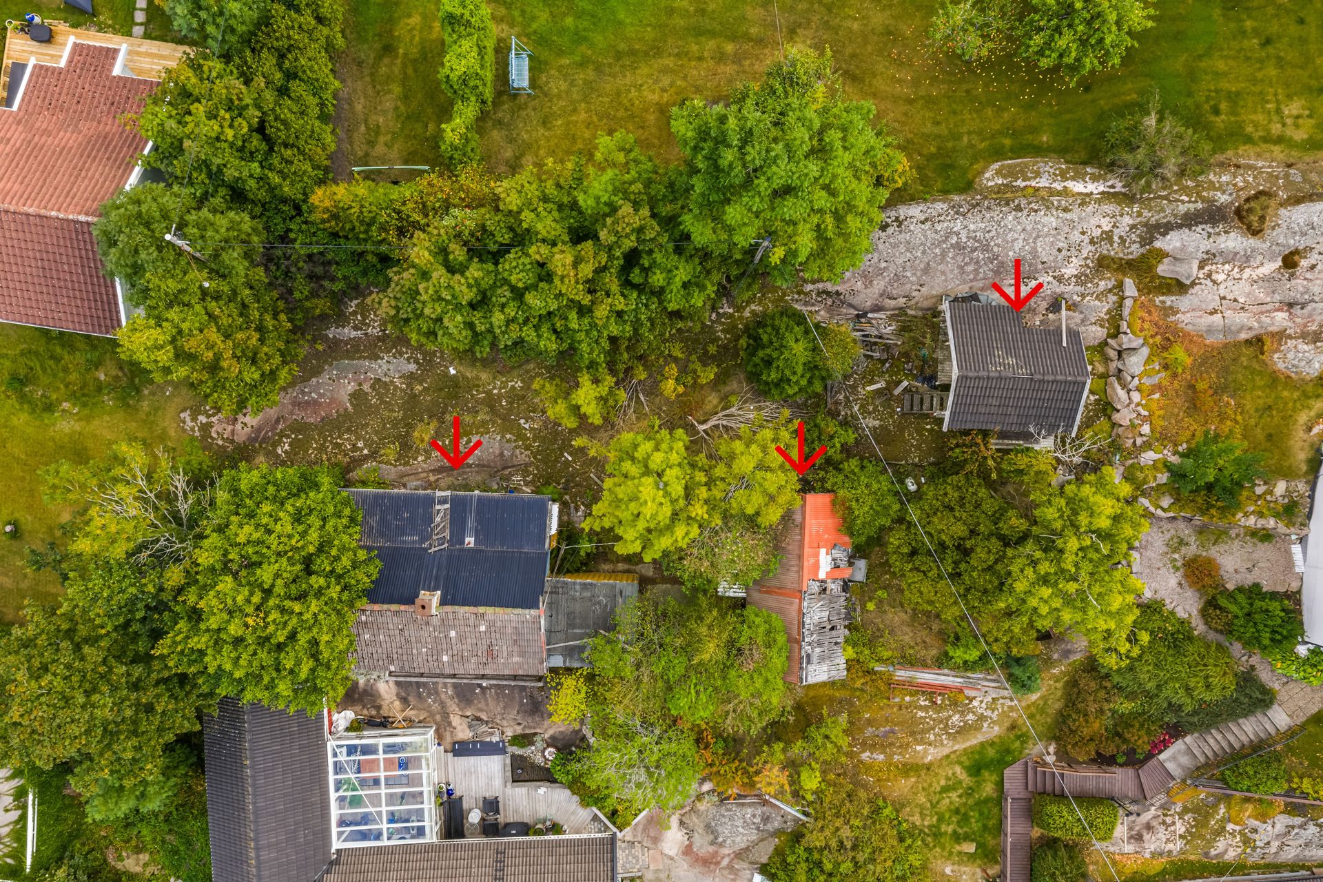 Tomten er omkranset av etablert bebyggelse og grønne lunger - Pilene viser eksisterende bygg på tomten.. Bilde nummer 3 av 3