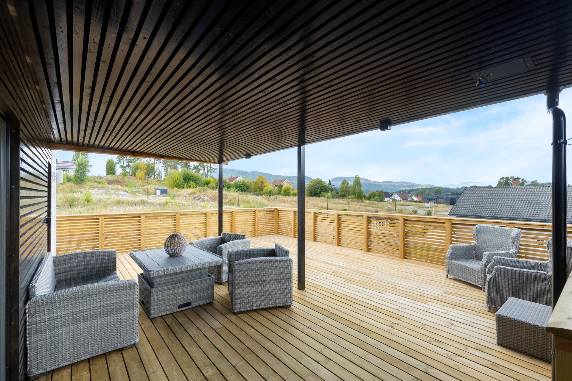 Fra stuen er det utgang til en stor, delvis overbygget terrasse med utsikt over landskapet.. Bilde nummer 3 av 3