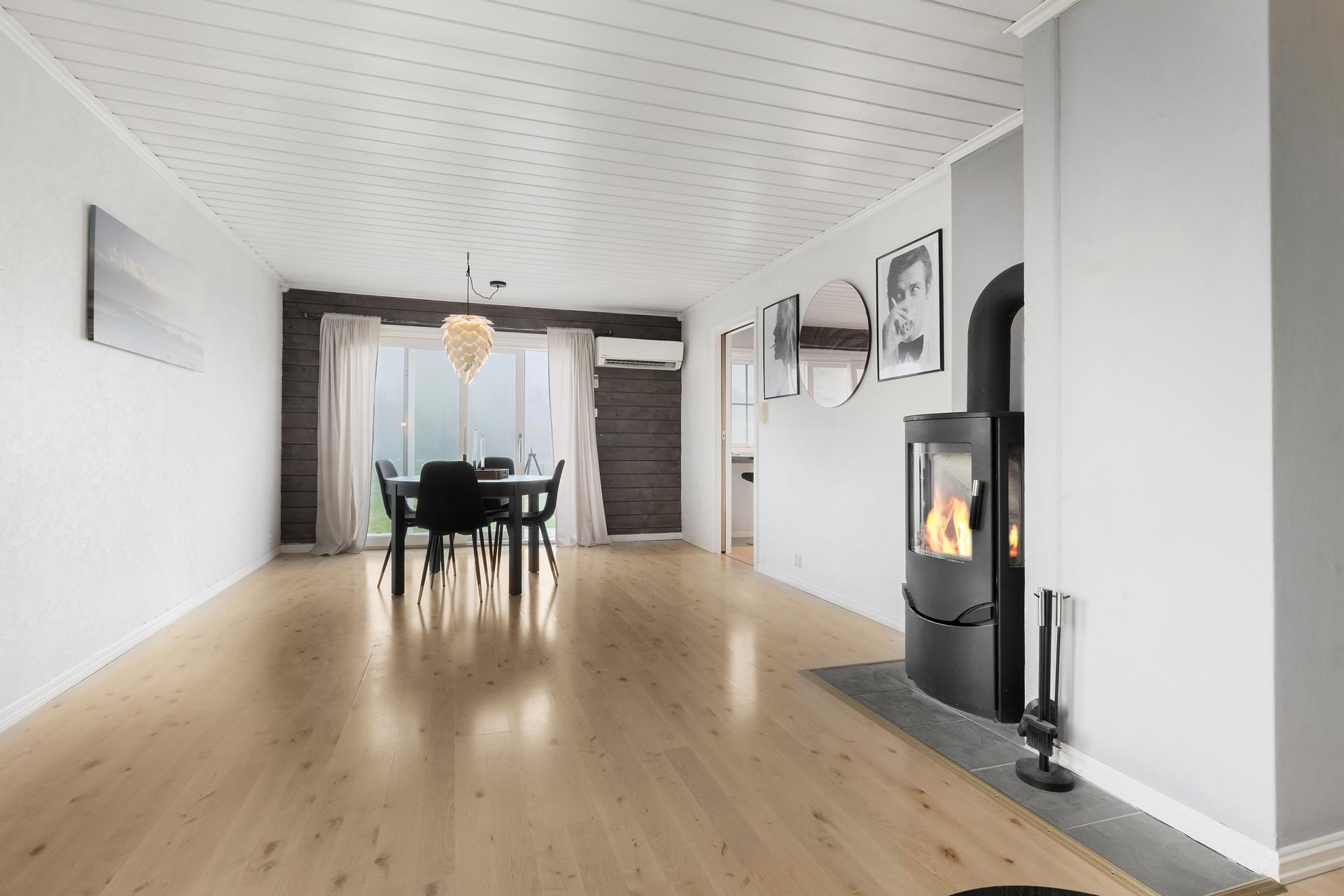 Bustaden har ei open og lys stove- og eteløysing med peisomn og varmepumpe.. Bilde nummer 3 av 3