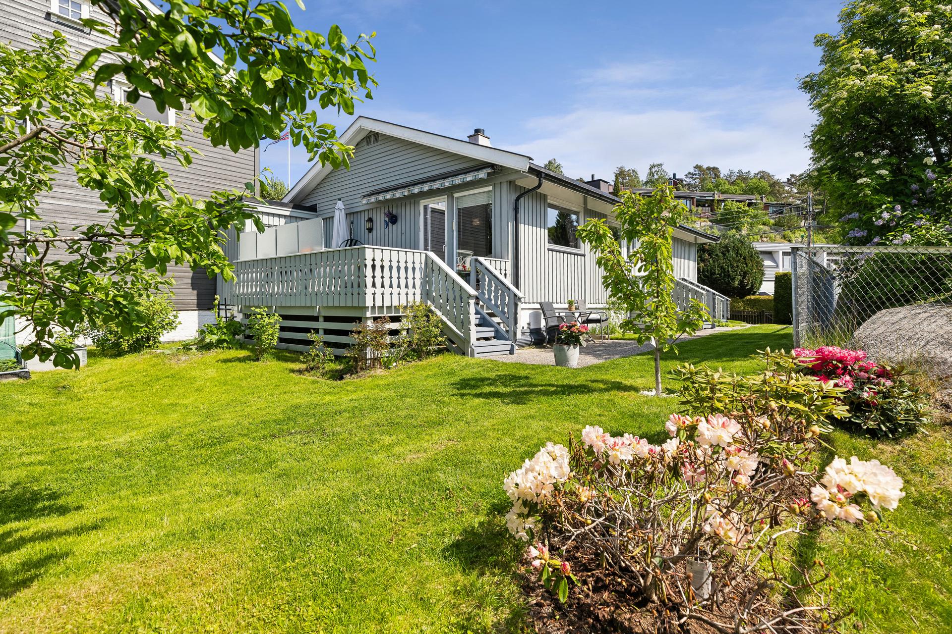 Eiendommen har en opparbeidet hage med gressplen, blomstrende beplantning og terrasse tilknyttet stuen.. Bilde nummer 2 av 3