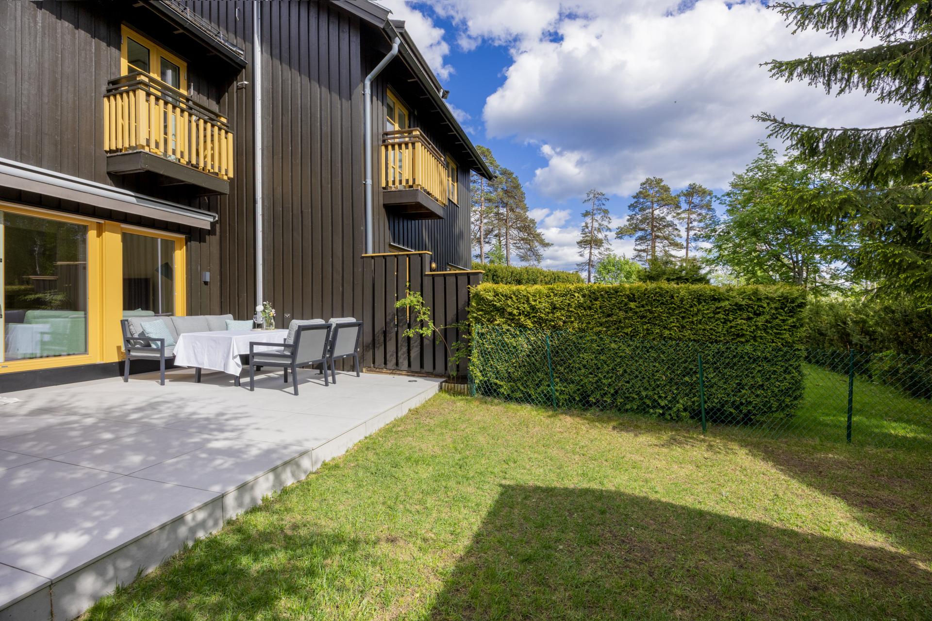 Fra stuen er det utgang til en romslig, flislagt terrasse og en skjermet hage. Boligen har integrert garasje og biloppstillingsplass.. Bilde nummer 3 av 3