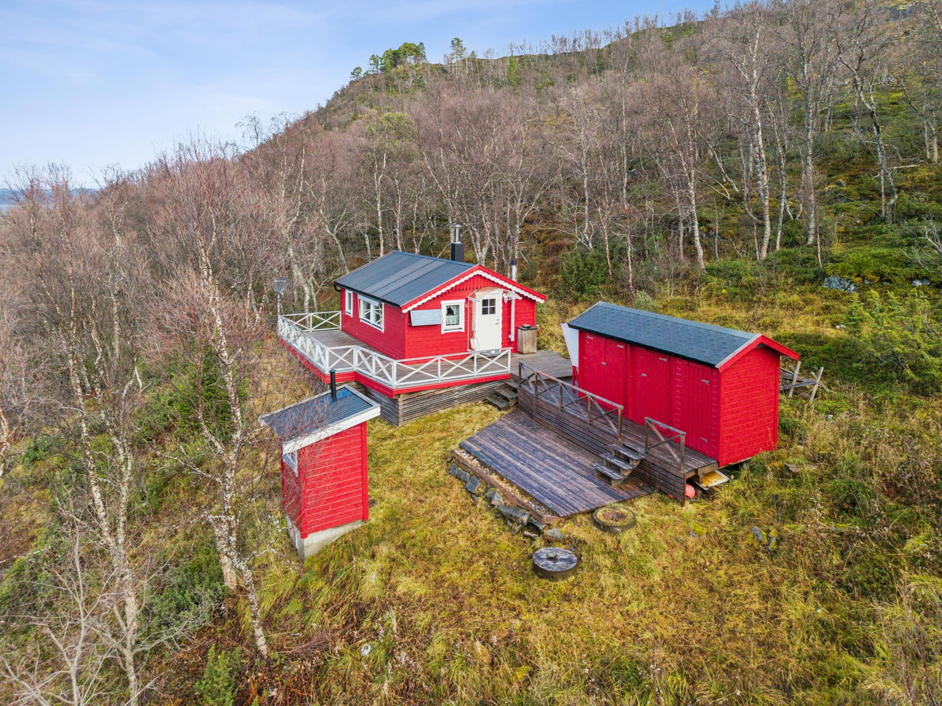 Uteområdet binder hytta sammen med uthus og utedo via sammenhengende terrasseplattinger.. Bilde nummer 2 av 3