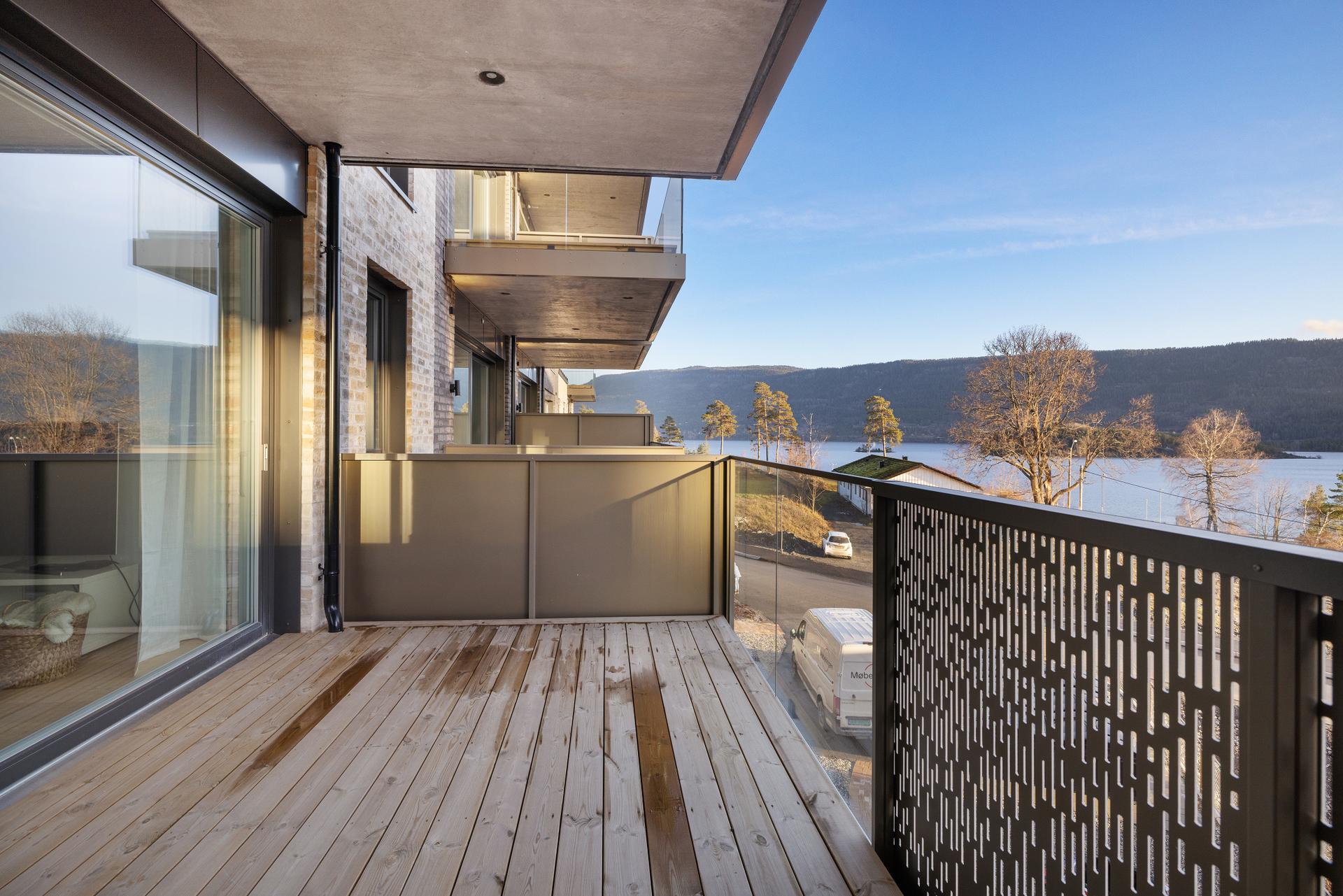 Terrassen utenfor stuen er bygget med terrassebord og har rekkverk i metall og glass.. Bilde nummer 2 av 3