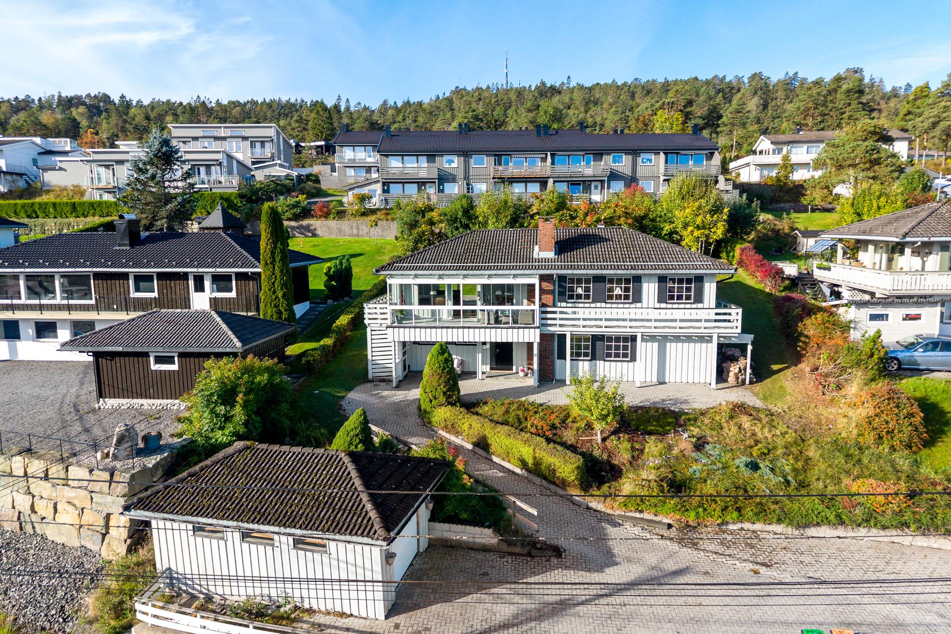 Eiendommen ligger i skrånende terreng med opparbeidet hage og belegningsstein.. Bilde nummer 3 av 3