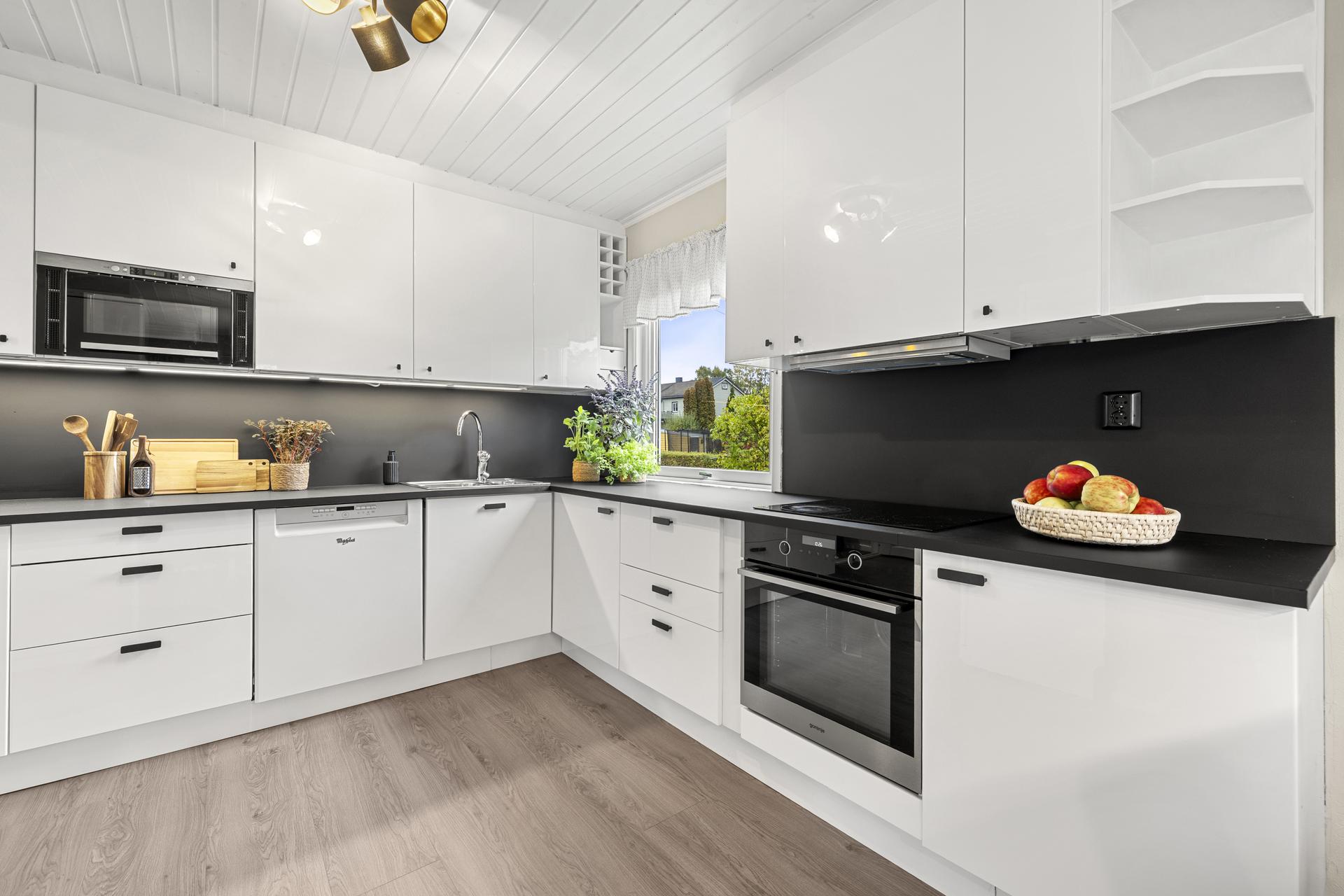 IKEA kjøkkeninnredning med glatte høyglansfronter og mørk benkeplate.. Bilde nummer 2 av 3