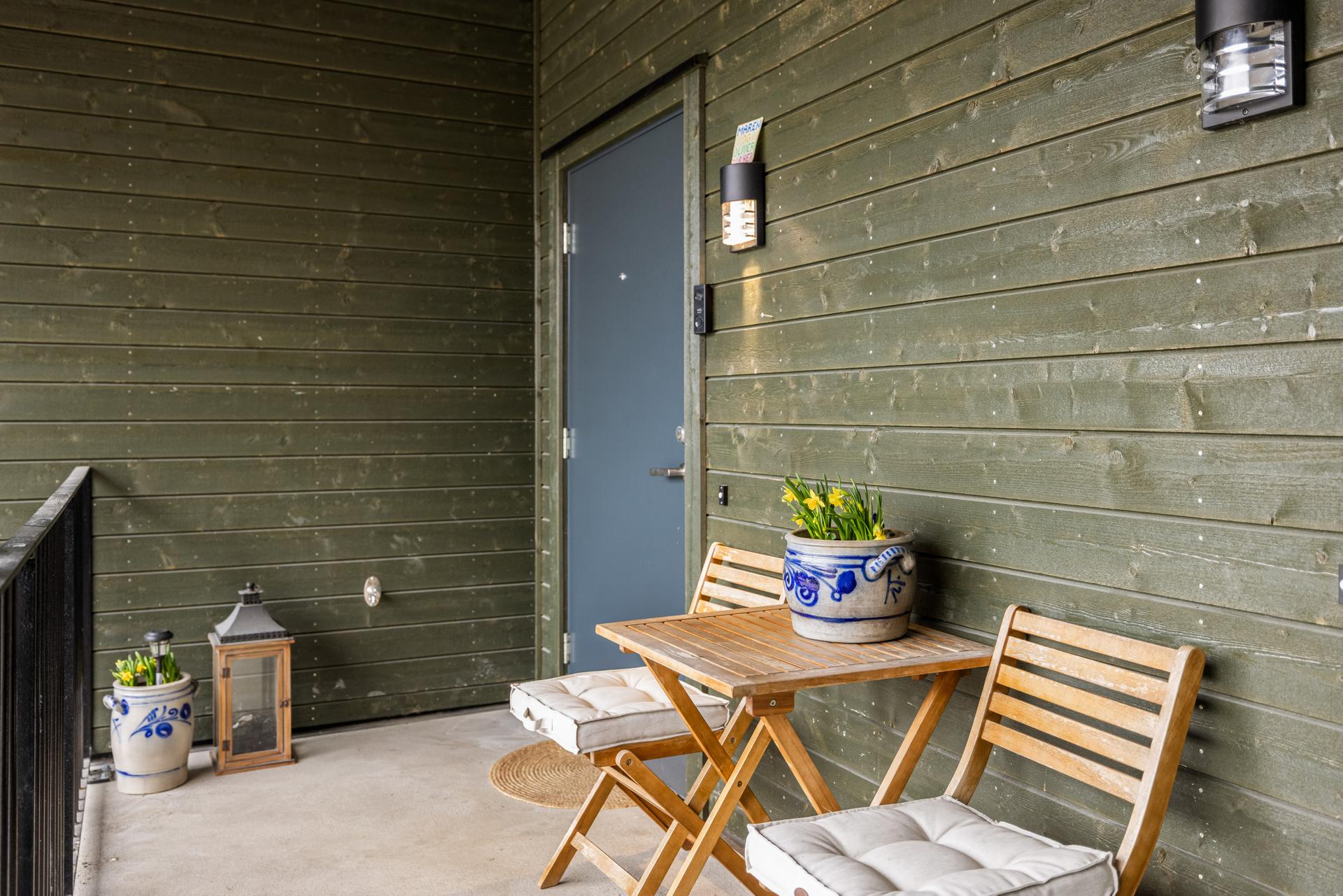 Leiligheten har en skjermet og overbygget inngang fra svalgangen, med plass til en liten sittegruppe.. Bilde nummer 3 av 3
