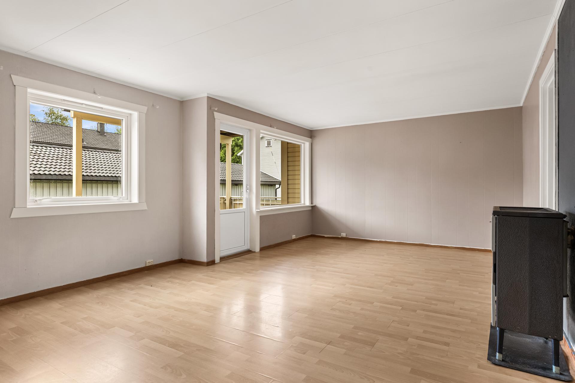 Stue med god plass til sittegruppe og direkte utgang til verandaen, hvor det videre nedgang til platting på bakkeninvå.. Bilde nummer 2 av 3