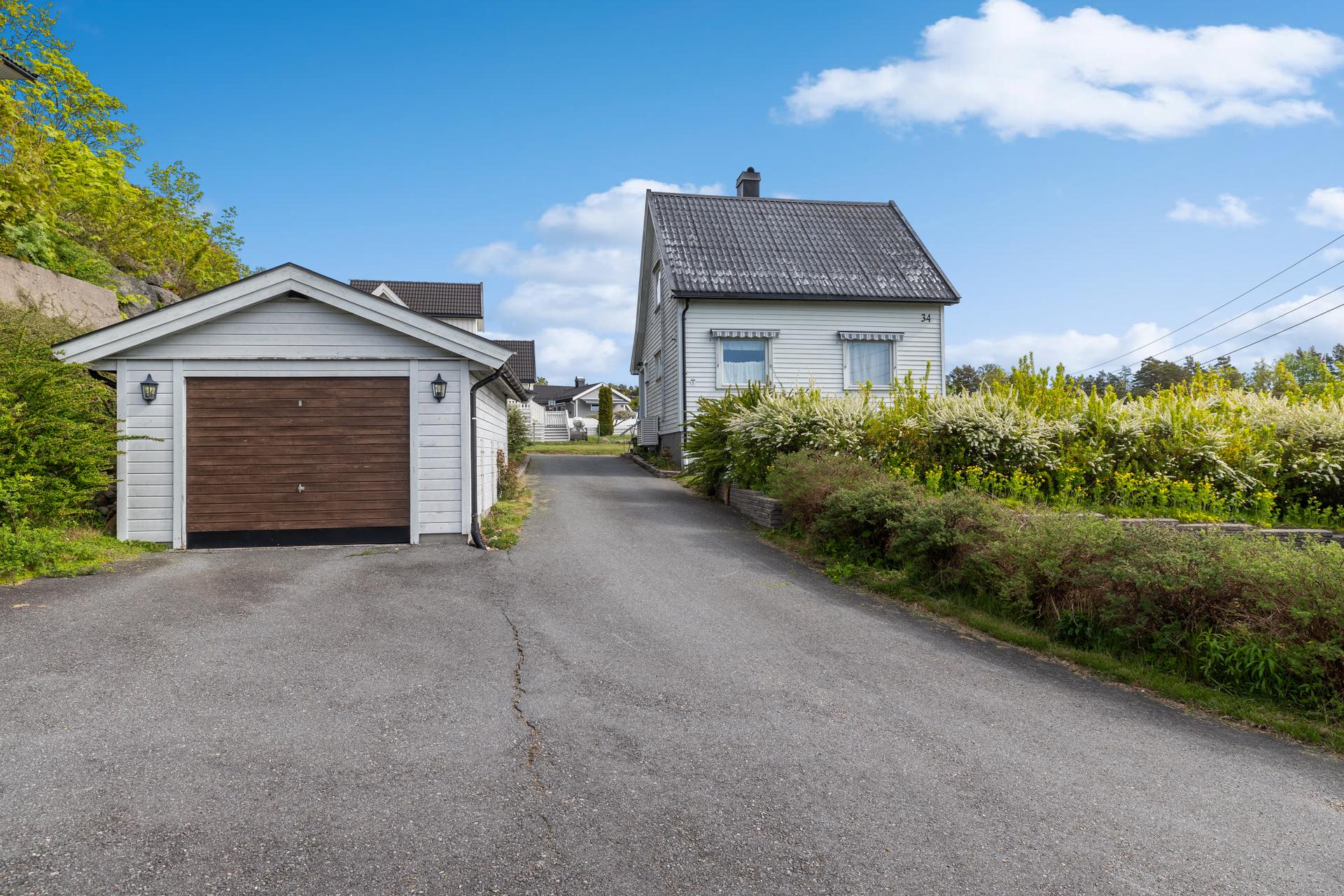 Uteområdet er pent opparbeidet med asfaltert gårdsplass som gir gode parkeringsmuligheter, samt plenarealer og variert beplantning som skaper en hyggelig og grønn ramme rundt boligen. Bilde nummer 3 av 3