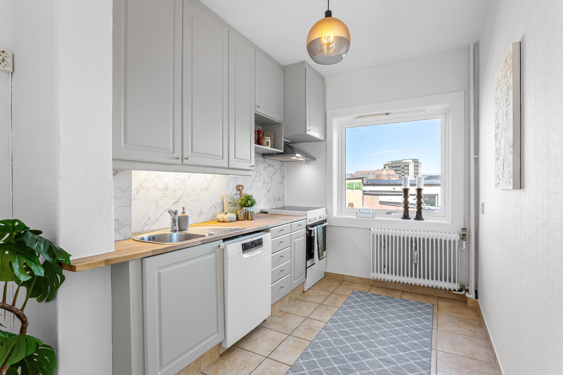 Leiligheten har et pent kjøkken som er oppgradert i 2026, med malte fronter, benkeplate i heltre, marmormønstret kitchen wall panel, ny taklampe og ny kjøkkenventilator. Frittstående hvitevarer medfølger i handelen.. Bilde nummer 3 av 3