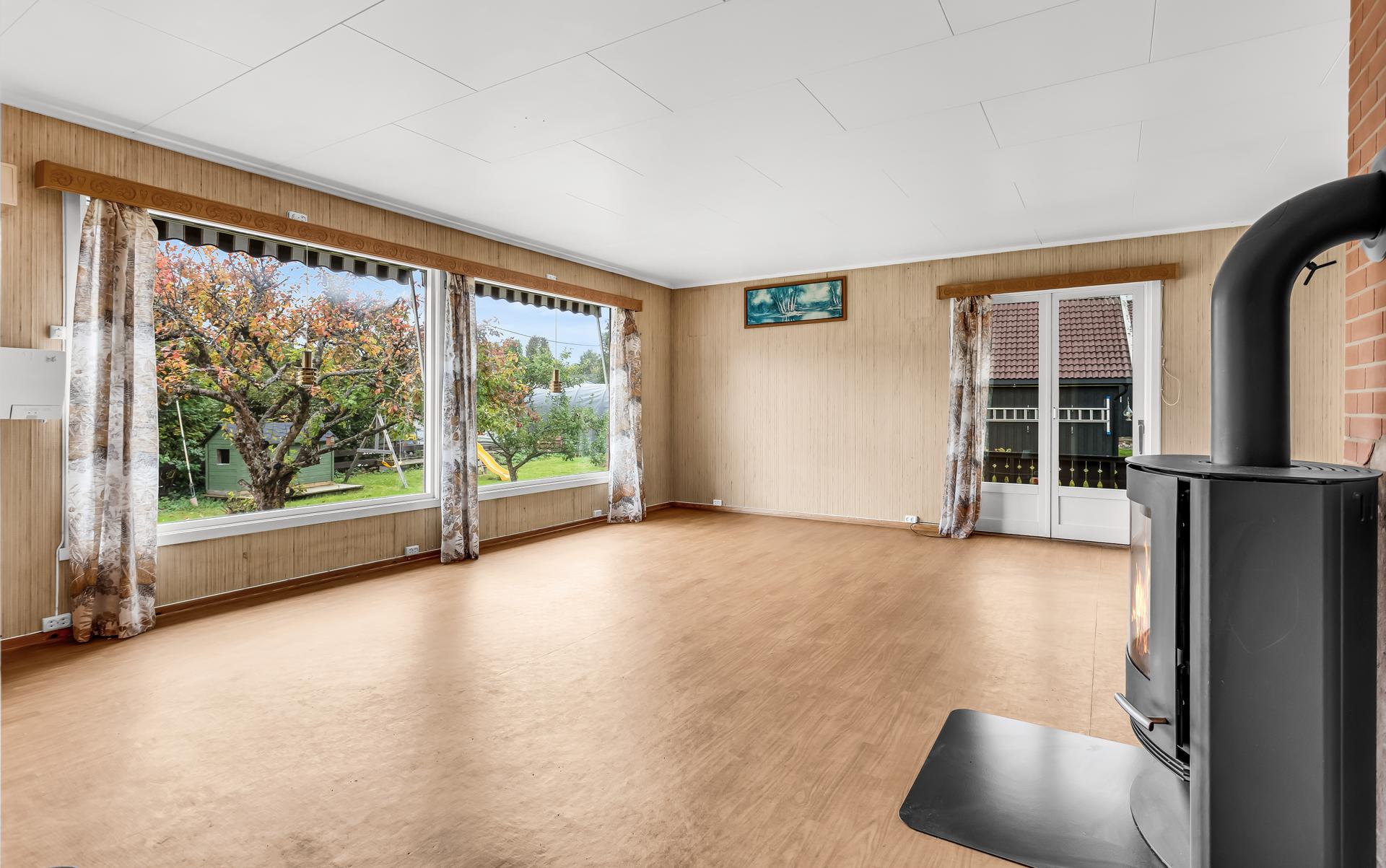 Stuen har peisovn og god plass til både sittegruppe og spisebord.. Bilde nummer 2 av 3