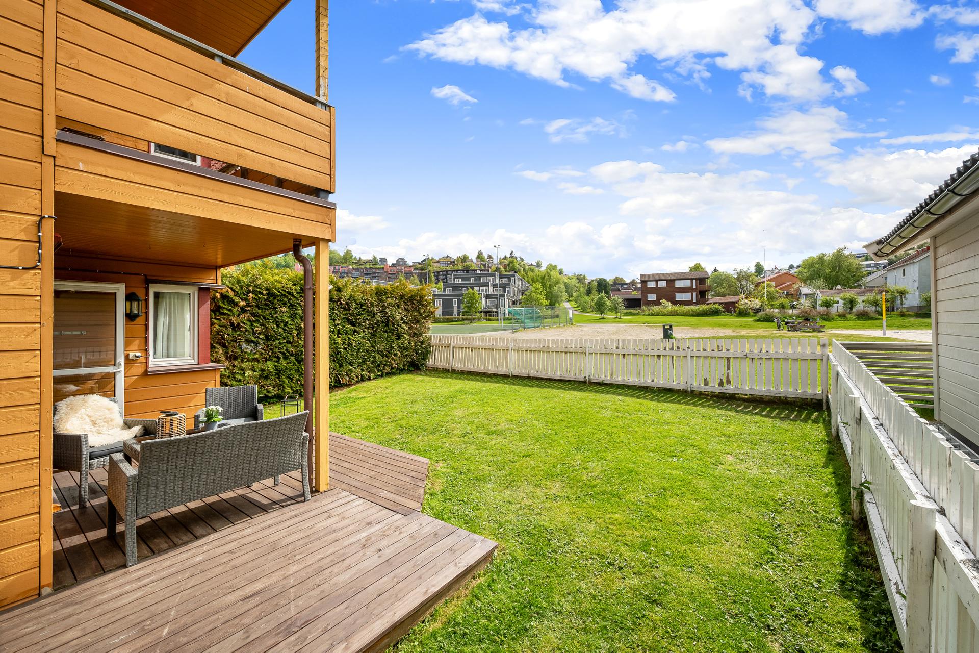 Her får du en solrik terrasse på 23 m², med nedgang til inngjerdet hage, som vender ut mot et stort og åpent friområde. . Bilde nummer 3 av 3