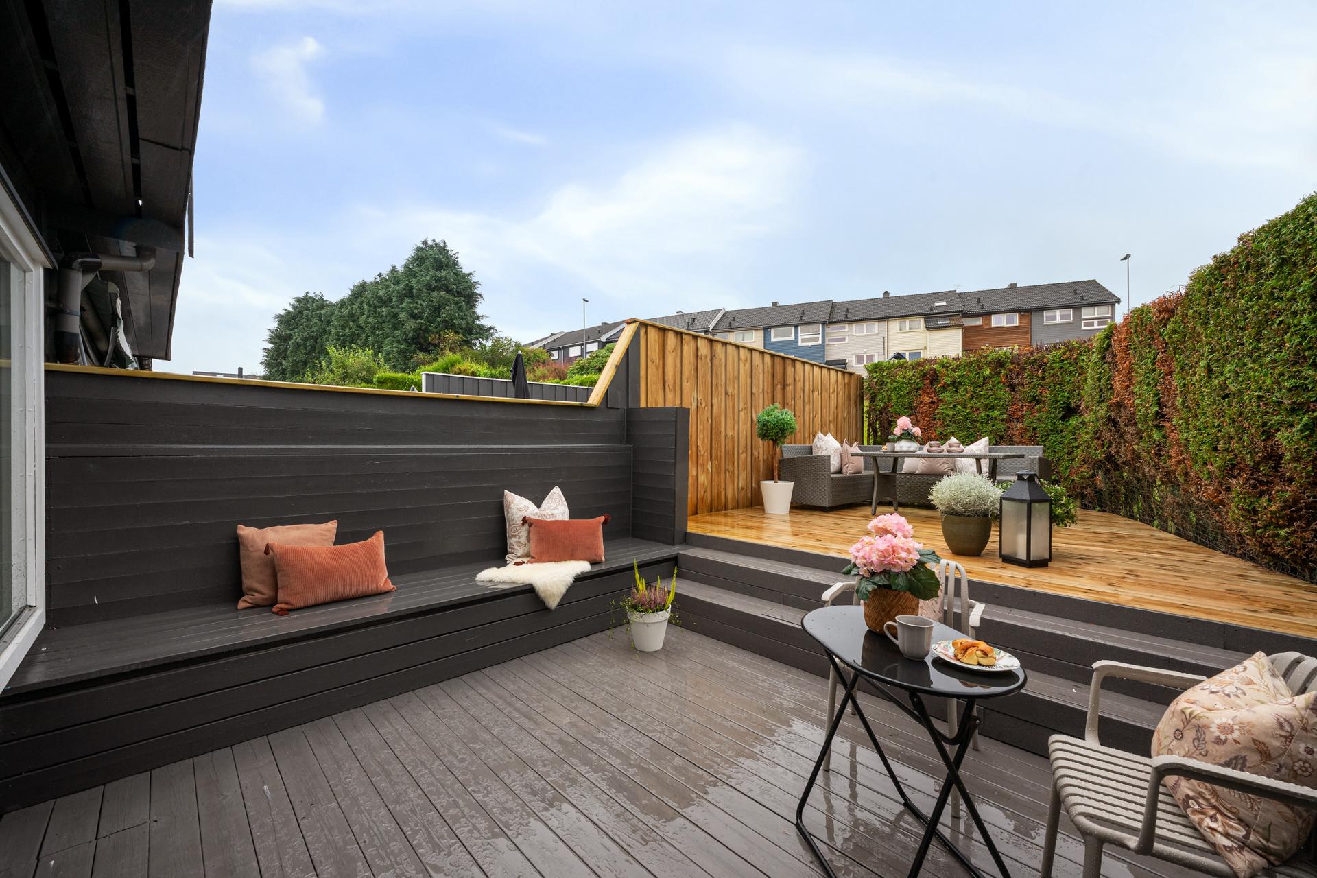 Rekkehuset byr på flotte uteområder, og på baksiden finner du en nivådelt terrasse med god plass til flere sittegrupper. Terrassen er skjermet av hekk og gjerde, noe som skaper en privat og trivelig ramme for uteopphold.. Bilde nummer 2 av 3