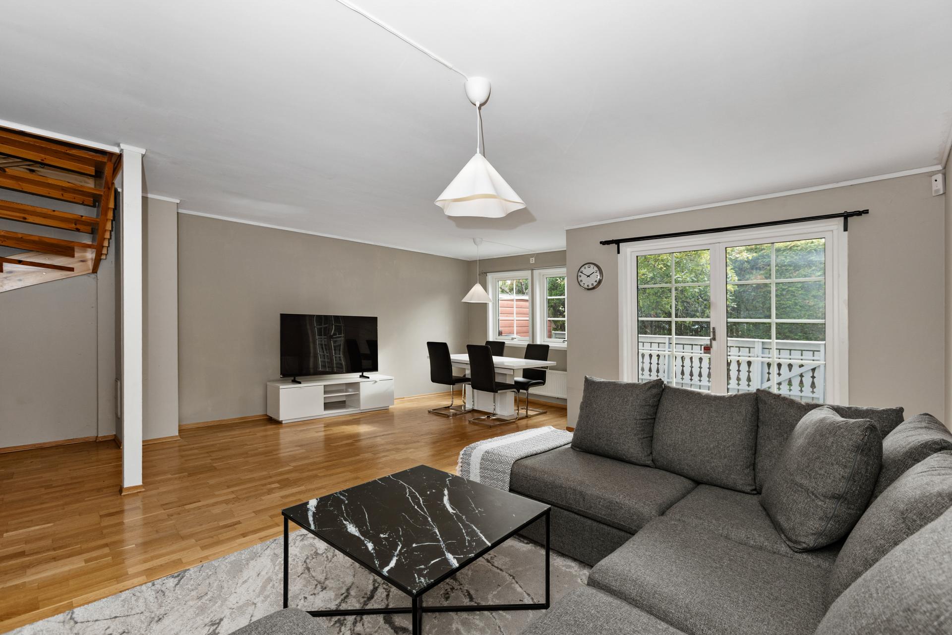 Stuen har god plass til både sofagruppe og spisebord, med direkte utgang til uteplassen.. Bilde nummer 3 av 3