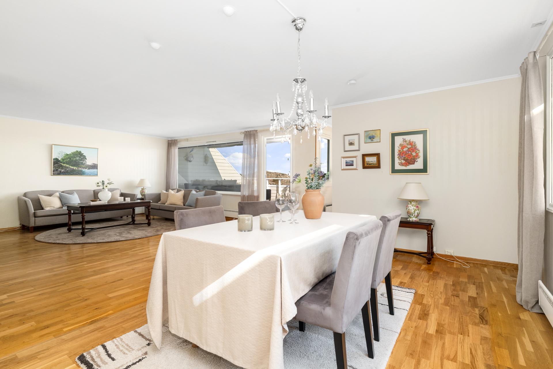 Stor stue og kjøkken med parkett på gulv, tapet på veggene og malt tak.. Bilde nummer 3 av 3
