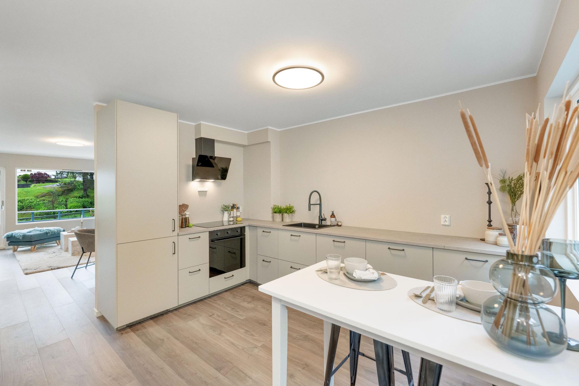Innredningen har glatte fronter, laminatbenkeplate og er utstyrt med platetopp, stekeovn og oppvaskmaskin.. Bilde nummer 2 av 3