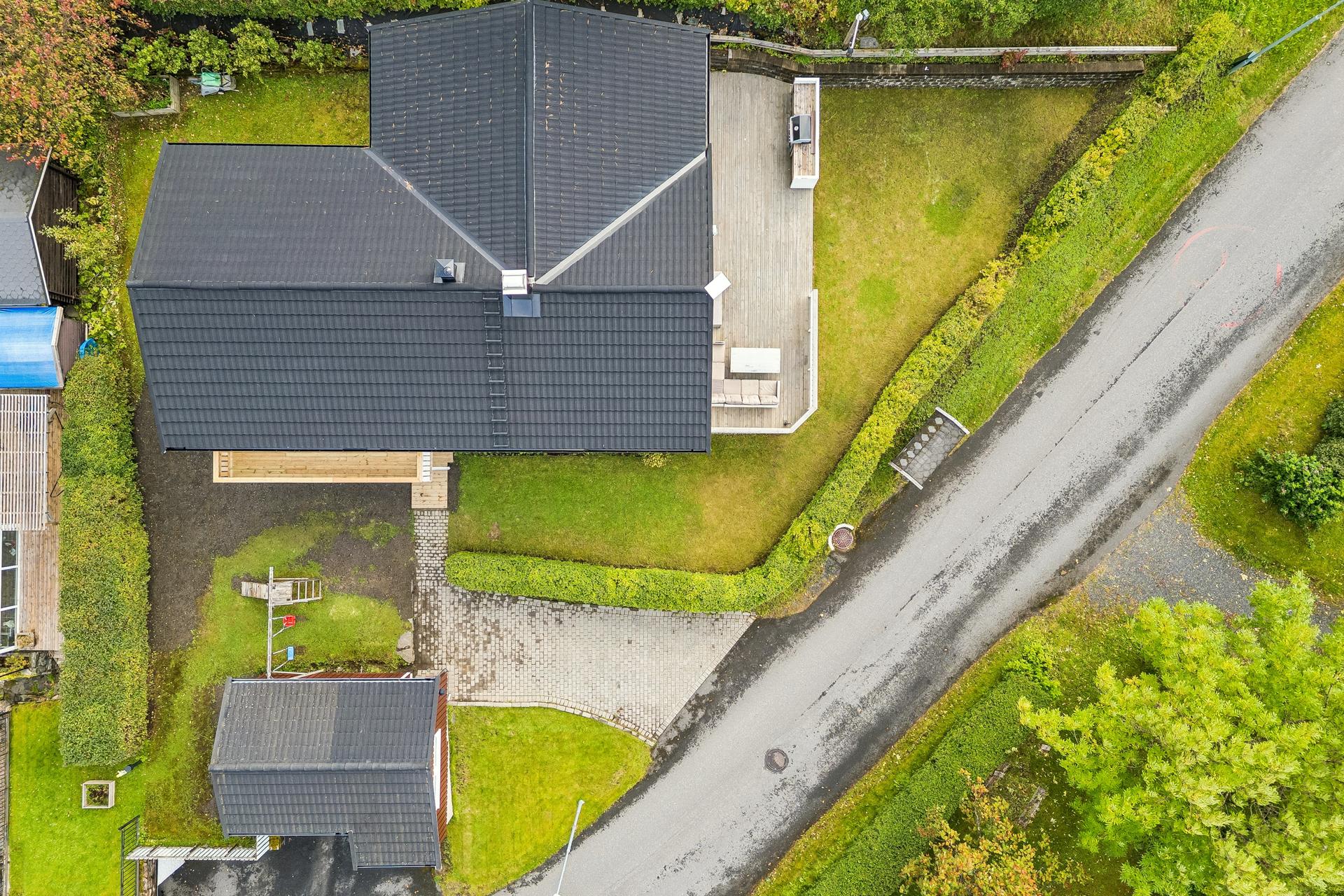 Oversikt over tomten med bolig, terrasse, hage og brosteinsbelagt adkomst. Det er nylig sådd nytt gress utenfor inngangspartiet.. Bilde nummer 3 av 3