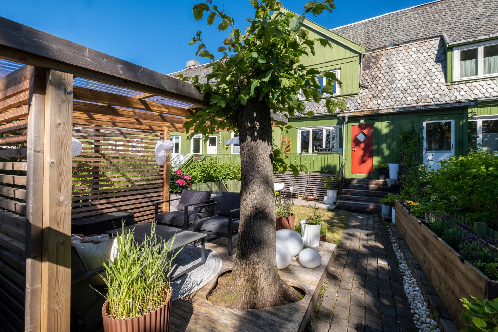 En flott og allsidig hage med plen, terrasser og brosteinsbelagte partier. Her finner du pergola, uthus, vakker beplantning, trær og praktiske blomsterkasser for dyrking. En perfekt kombinasjon av hygge og grønne opplevelser.. Bilde nummer 3 av 3