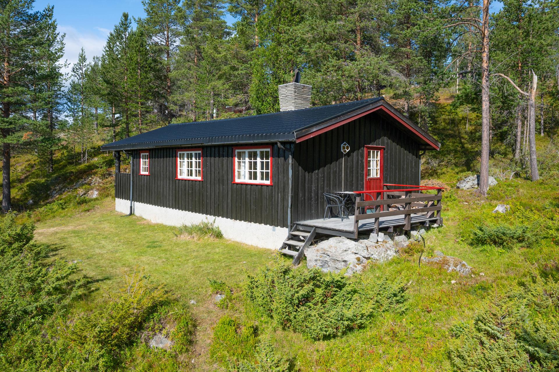Hytta har stående trekledning, overbygd inngangsparti og tilhørende utvendig bod. . Bilde nummer 3 av 3