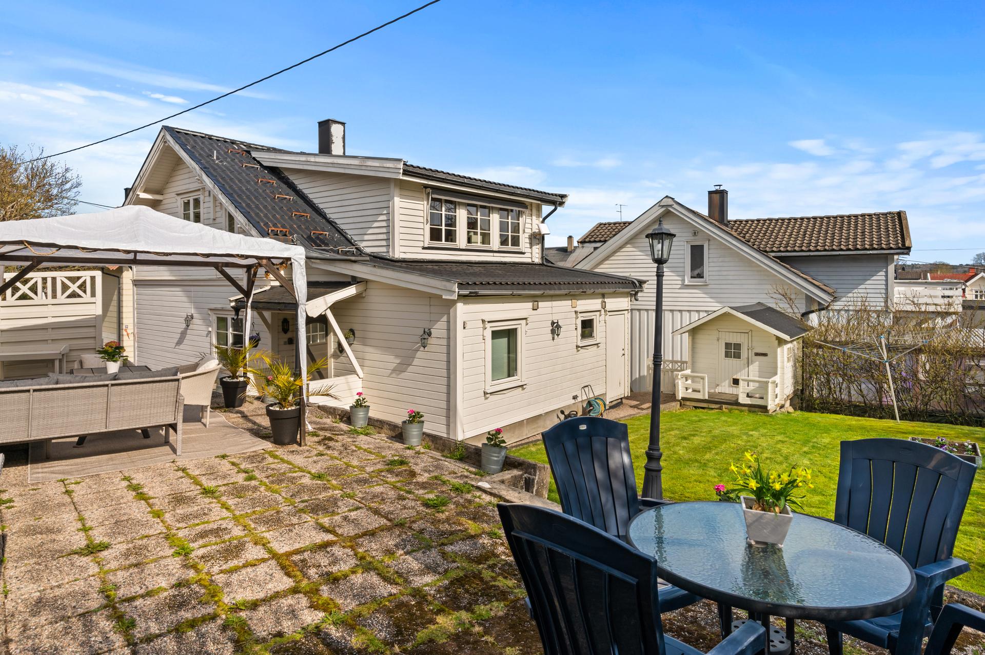 Eiendommen ligger på en skrånende tomt med en opparbeidet hage og flere soner for uteplasser.. Bilde nummer 2 av 3