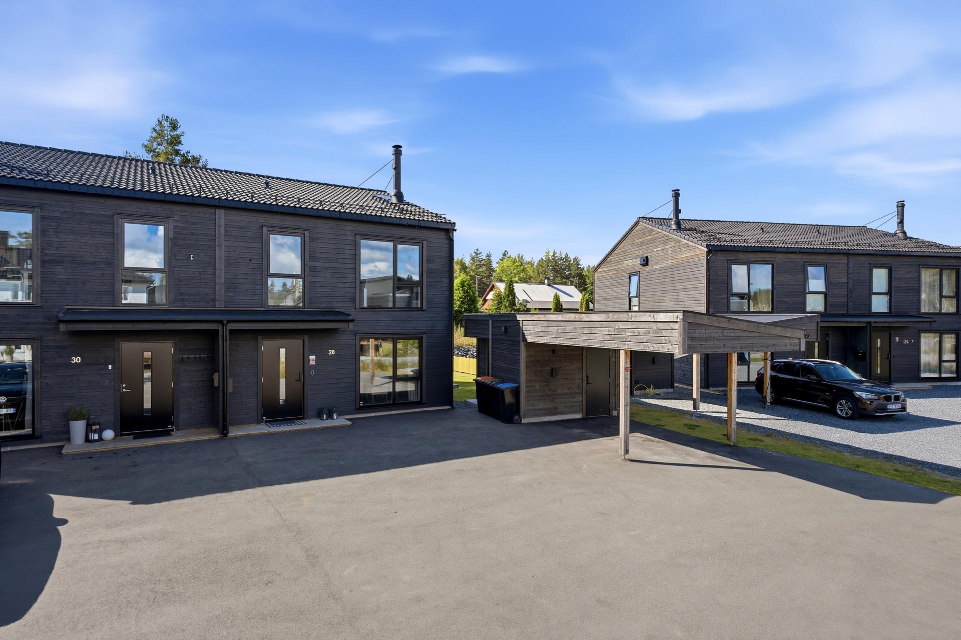 Det er gode parkeringsmuligheter i carport og på asfaltert gårdsplass. Bilde nummer 3 av 3
