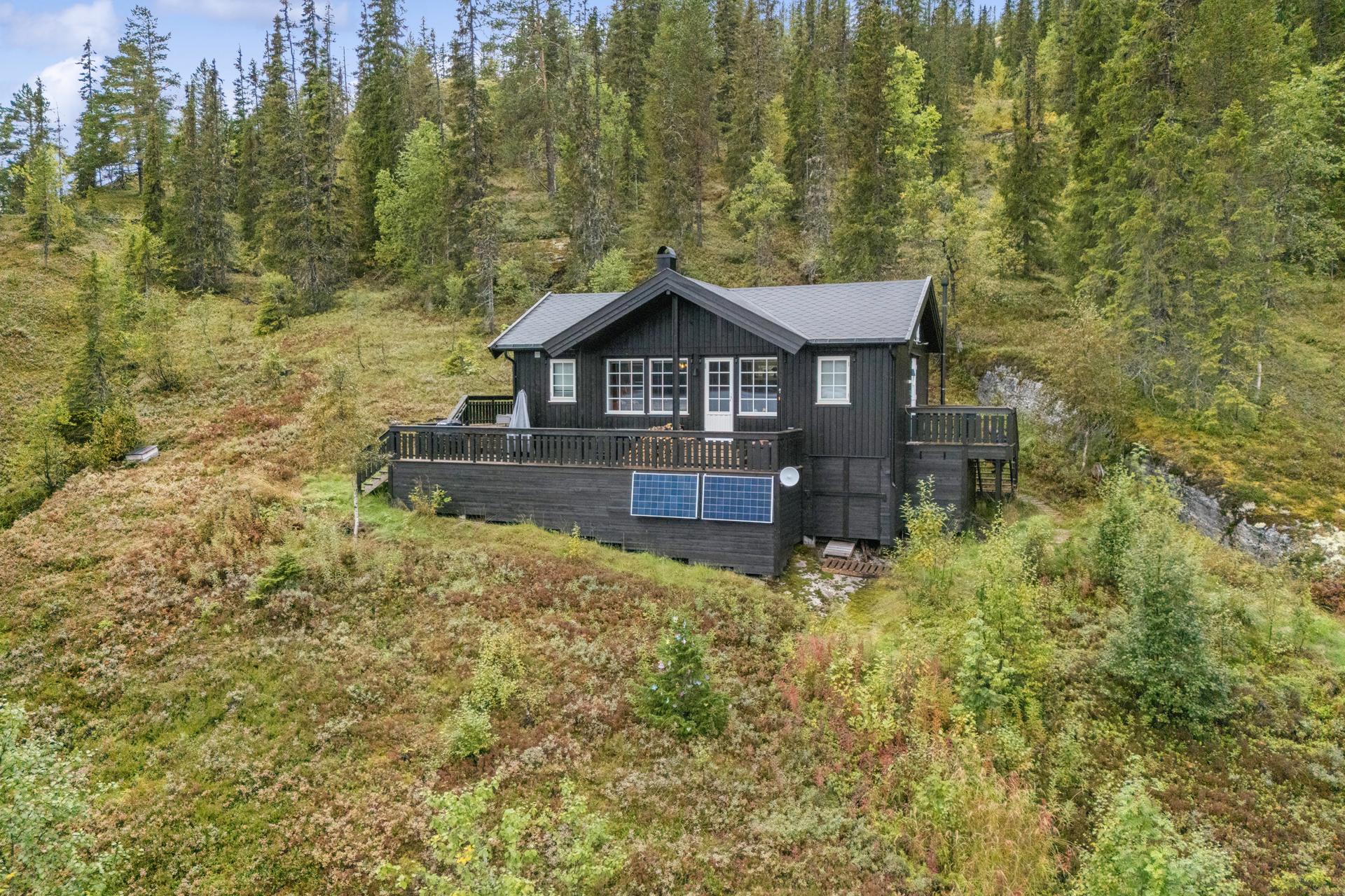 Frittliggende hytte med usjenert plassering i terrenget og store terrasseflater.. Bilde nummer 2 av 3