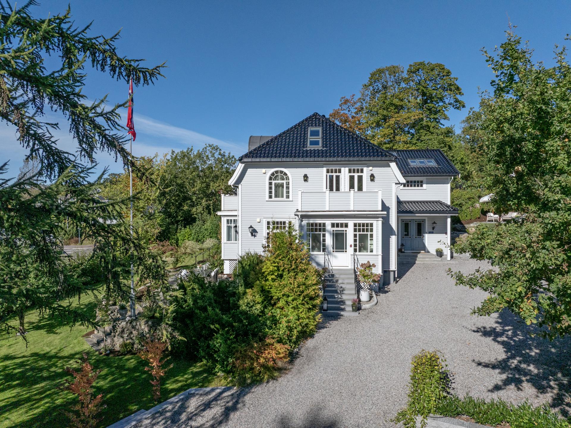 Villaens harmoniske arkitektur, karakteristiske takform og elegante vindusløsninger gir et imponerende førsteinntrykk. Bilde nummer 2 av 3