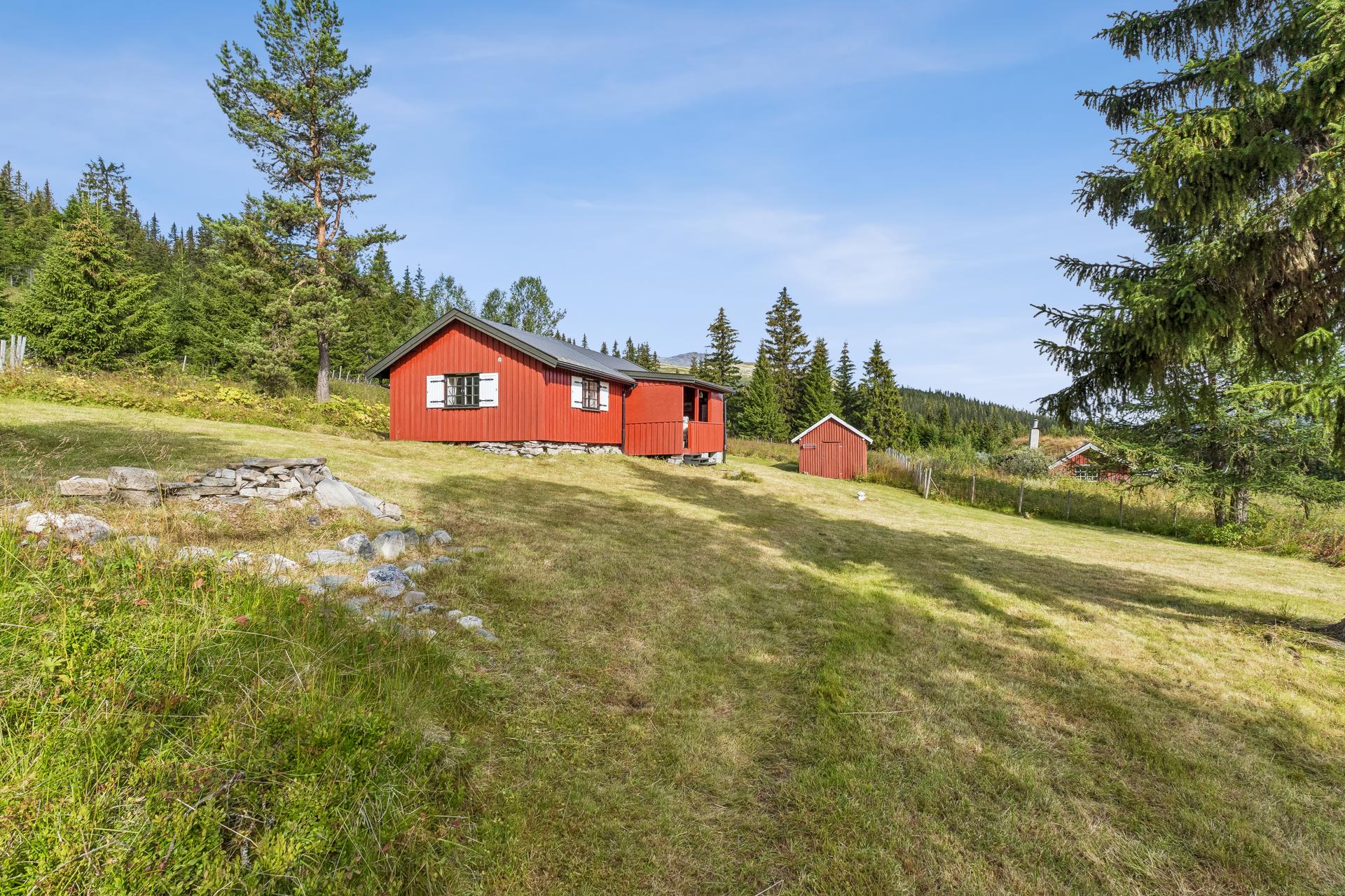 Tomten er skrånende og opparbeidet med plen og gjerde.. Bilde nummer 2 av 3