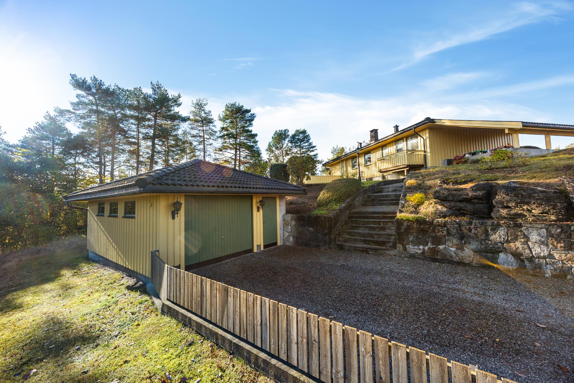 Frittliggende garasje oppført i 1984, med gruset innkjøring og trapp opp til boligen.. Bilde nummer 3 av 3
