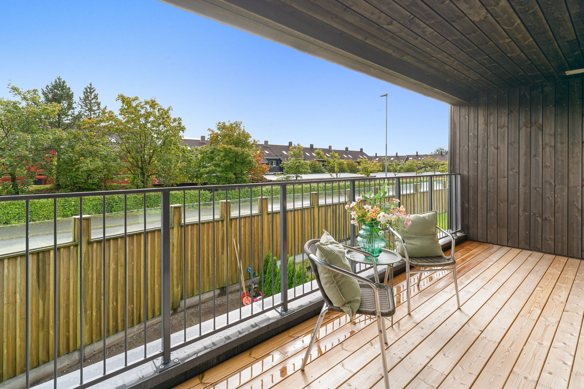 Fin og lun terrasse ut fra stue med utsikt over nærområdet. Overbygget tak, skjermet for vær og vind. . Bilde nummer 2 av 3